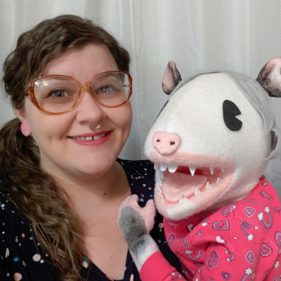 Photograph of Amanda posing with one of her handmade puppets.